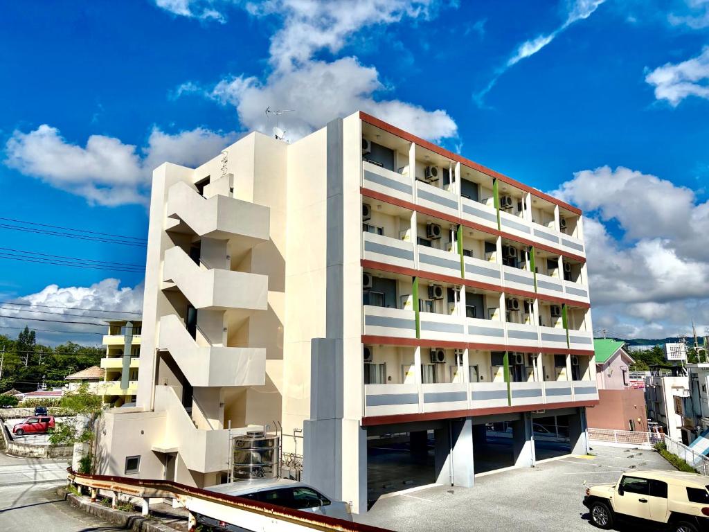 a white building with balconies on the side of it at HOTEL Progress inn 名護 MATABee in Nago