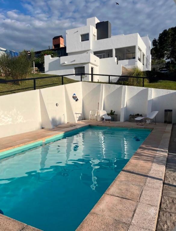 a villa with a swimming pool in front of a house at Casablanca in Huerta Grande