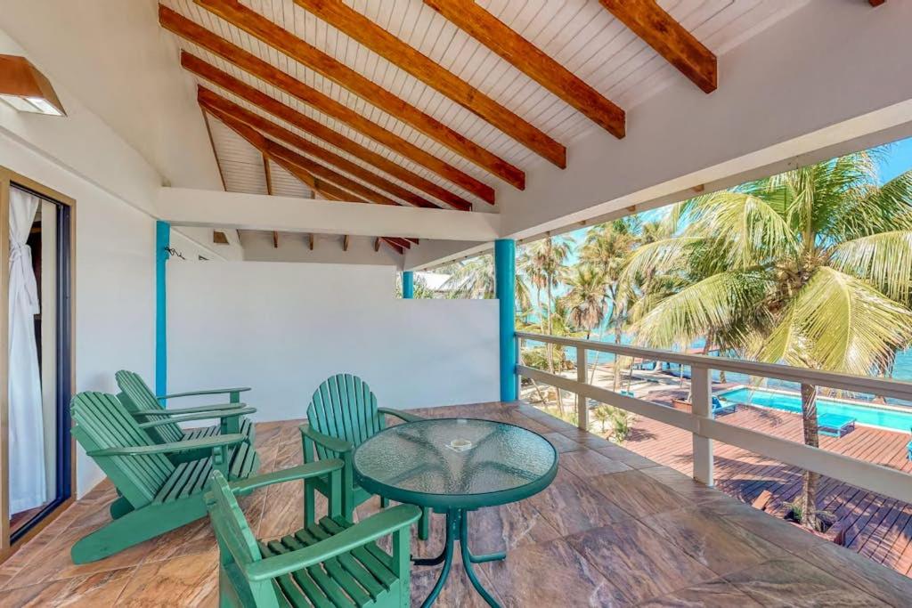a porch with green chairs and a table and a pool at Condo #23 @ Beachside Villas in Placencia