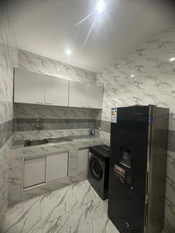 a kitchen with white marble walls and a refrigerator at Bayt Noor in Dakar