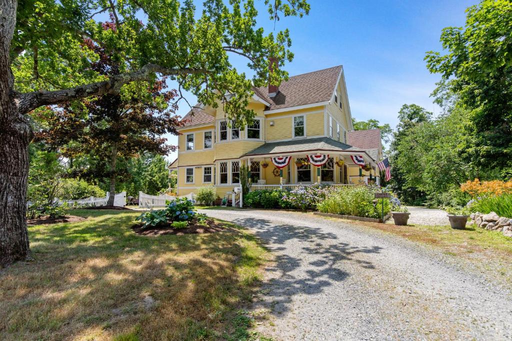 a large yellow house with a driveway at Inn at the Oaks in Eastham