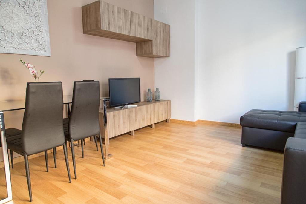 a living room with a table with chairs and a television at Apartamento Eursu centro con piscina in Málaga