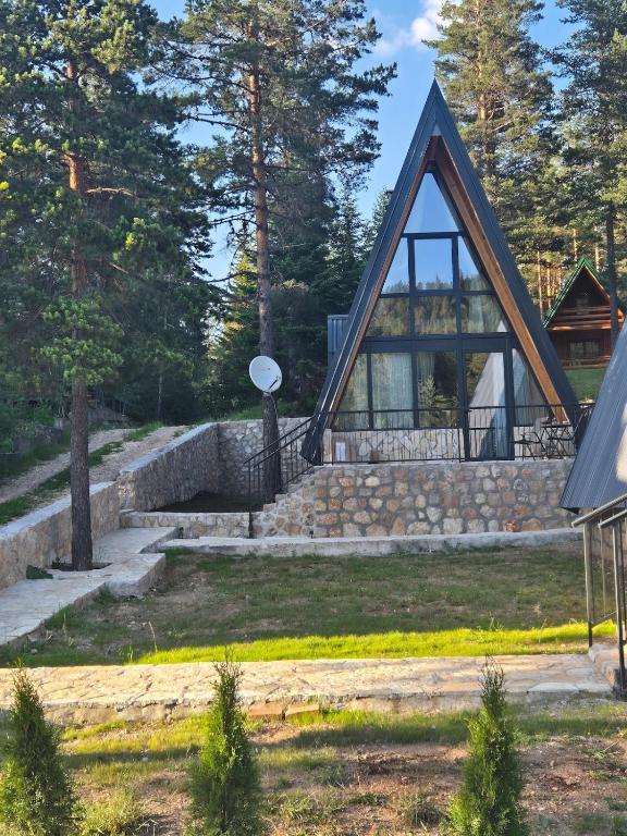 a house with a triangular roof and a stone wall at Villa Evergreen Žabljak in Žabljak
