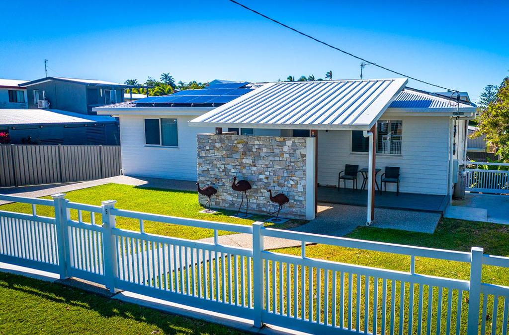 a white fence in front of a house with a roof at Zilzie Beach House in Zilzie