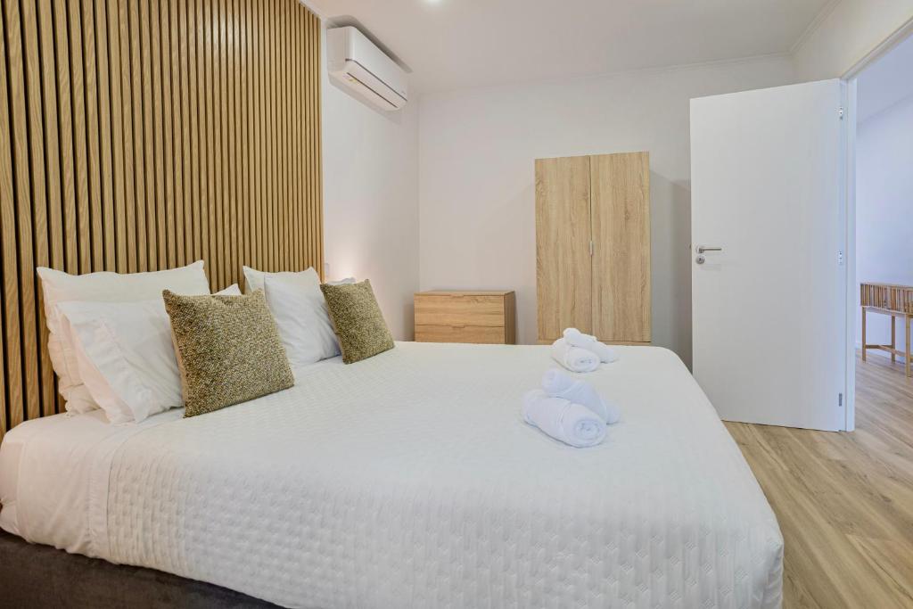 a bedroom with a white bed with a stuffed animal on it at Achadinha Sunset House - São Miguel, Açores in Achadinha