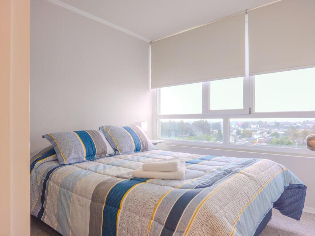 a bedroom with a large bed with blue and yellow stripes at Apart Total Aldunate Temuco Centro 2 in Temuco