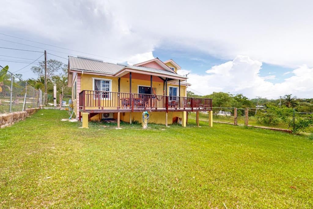 a yellow house with a deck on a yard at The Pine Tree Villa in San Ignacio