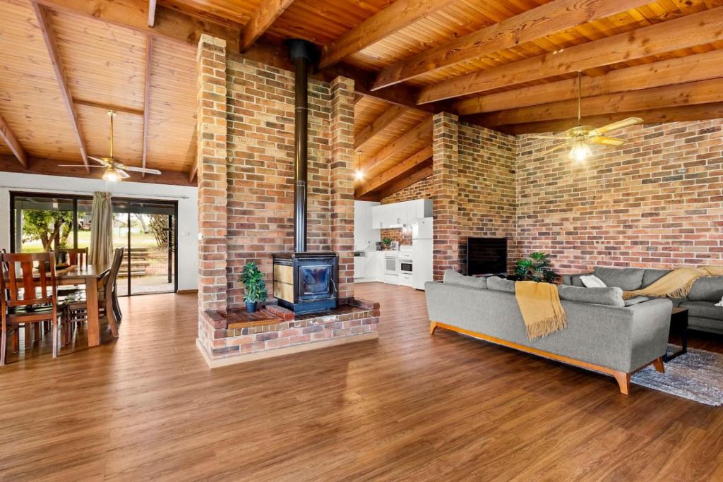 a living room with a brick wall and a fireplace at Hunter Valley 2 x Homes Pets Heated Pool in Whittingham