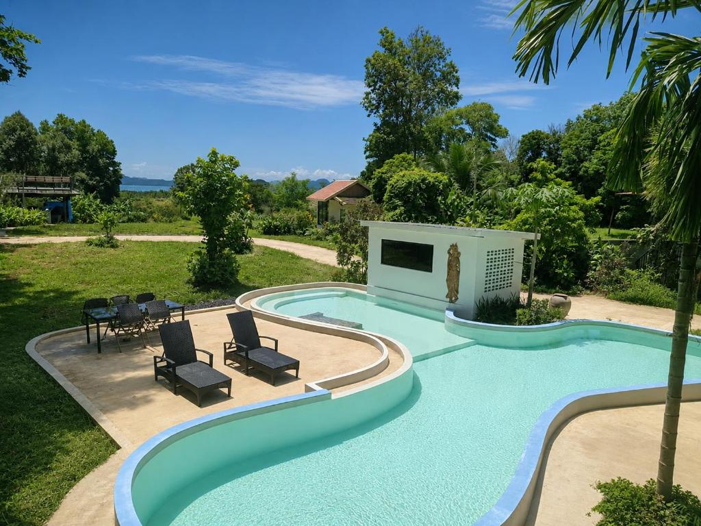 a swimming pool with two chairs and a table and chairs at Para Hill Homestay in Ban Muang Mai