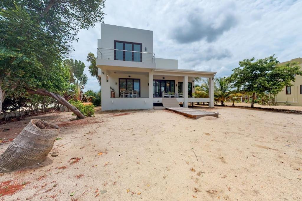 a large white house on a beach with trees at Green Tower House in Placencia