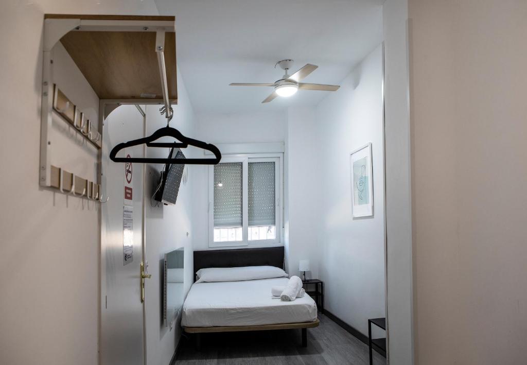 a small room with a bed and a ceiling fan at Metropolitano Guesthouse in Madrid