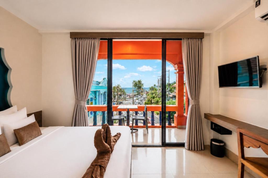 a hotel room with a bed and a balcony at Khaleej Mass Hotel Patong in Patong Beach