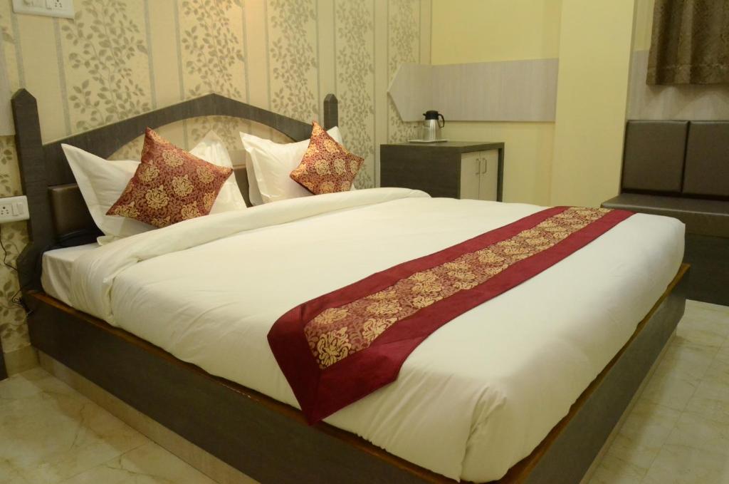 a bedroom with a large white bed with pillows at Hotel Rahil Palace in Varanasi