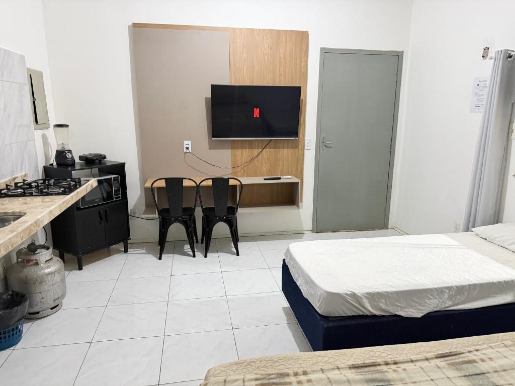 a room with a kitchen with a bed and a tv at Ap no Derby com garagem e ar in Sobral