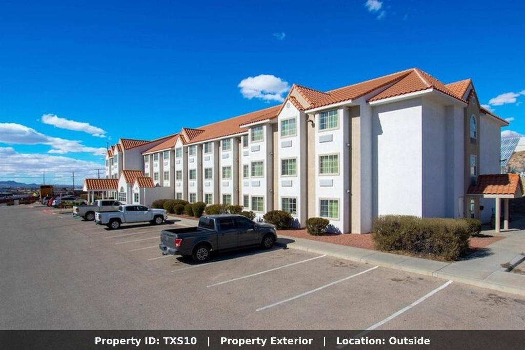a large white building with cars parked in a parking lot at El Paso Inn in Ysleta