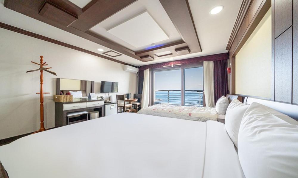 a bedroom with a white bed and a large window at Mobydick Hotel in Yangyang