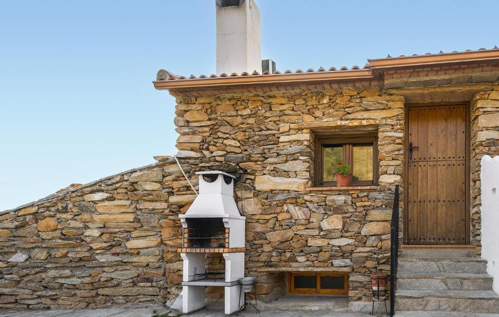 a stone building with a chimney and a stove at Jaraiz in Laroya