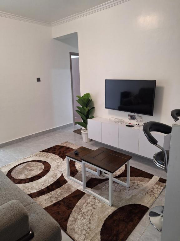 ein Wohnzimmer mit Fernseher, Sofa und Tisch in der Unterkunft Bloomstays Furnished Apartments Nairobi - Two Bedroom With Sauna Gym & Workspace in Nairobi