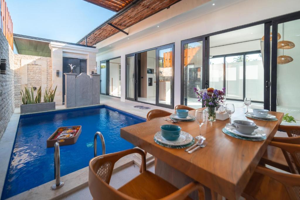 a dining room with a table and a swimming pool at Villa Toograss close to Black Sand Beach in Keramas
