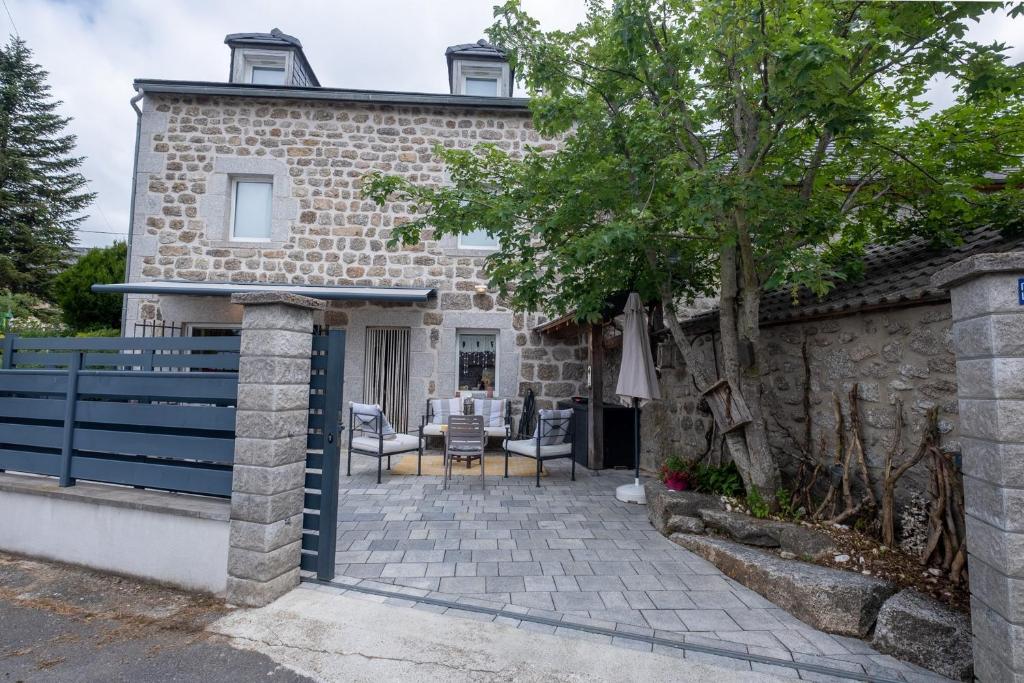 a stone house with a fence and a patio at Gîte oya in Chaudeyrac