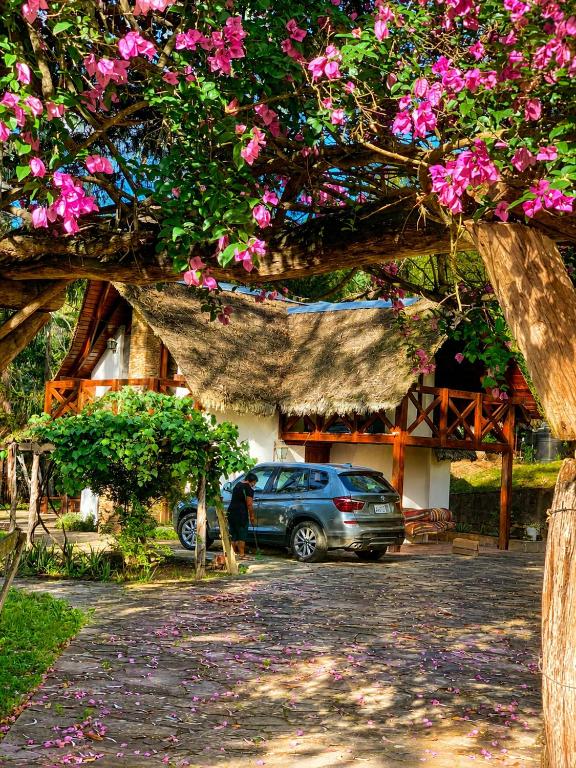 a car parked in front of a house with pink flowers at Valle Verde Lodge - Bosque in Samaipata