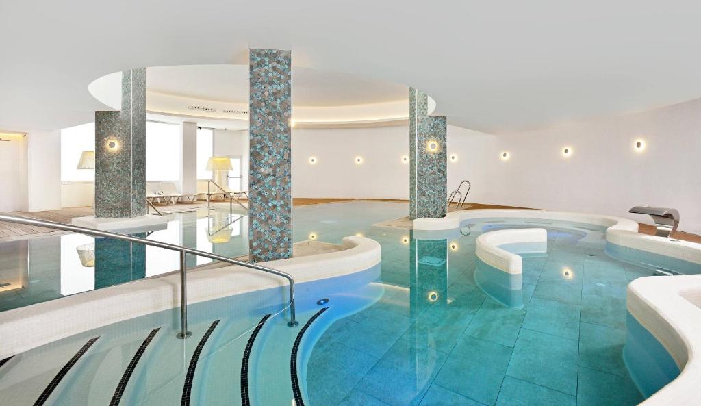 a pool with two hot tubs in a room at SOL by Meliá Torremolinos - Don Pedro in Torremolinos