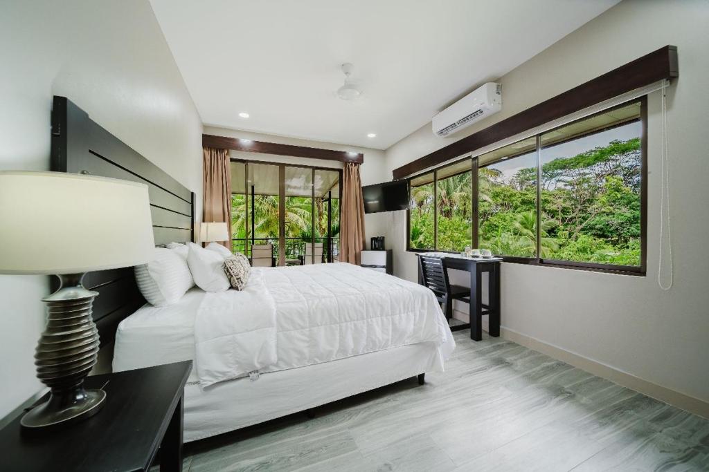 a bedroom with a white bed and a desk with a lamp at Buena Vista Plus in Quepos