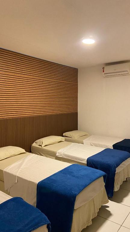 a room with three beds with blue sheets at Pousada Recife Tropical in Recife