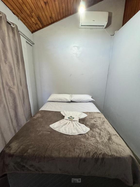 a small bedroom with a bed with a dress on it at Pousada Bonetti Quarto 8 in Santa Rosa