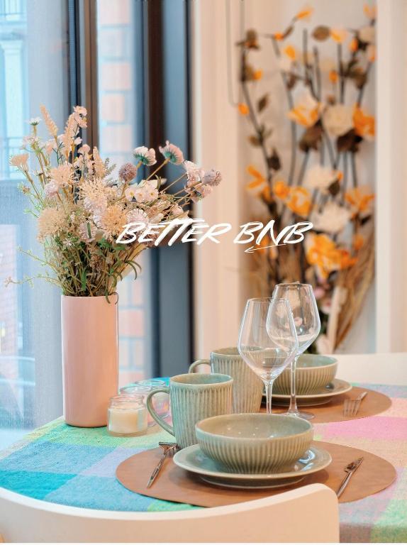 a table with plates and glasses and a vase with flowers at Bloom Central – Pool & Gym in Wellington