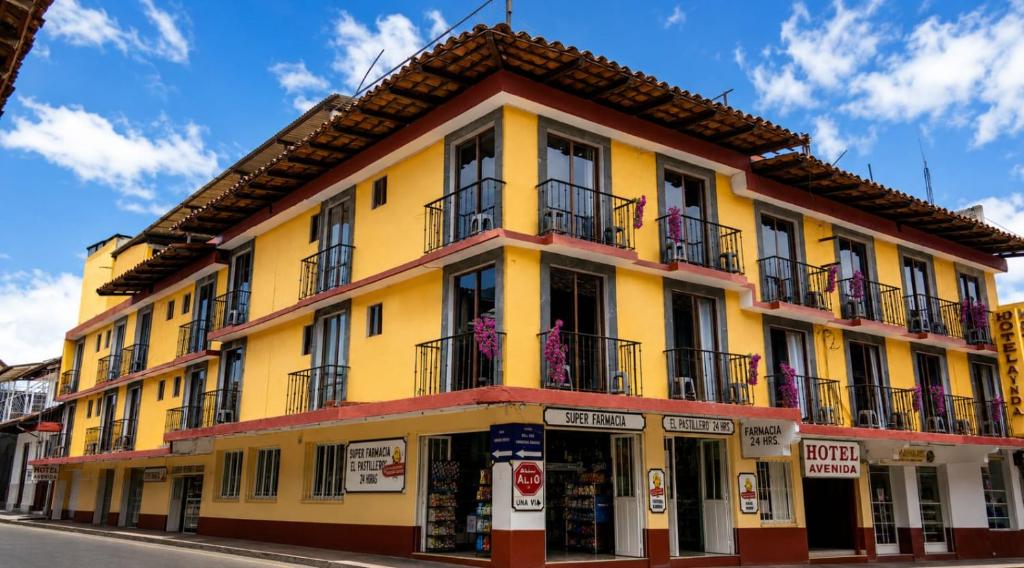 a yellow building with balconies on a street at Hotel Avenida in Zacatlán