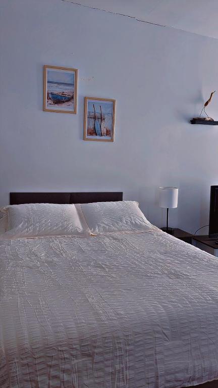 a white bed in a bedroom with two pictures on the wall at Ocean Spray Inn in Winthrop