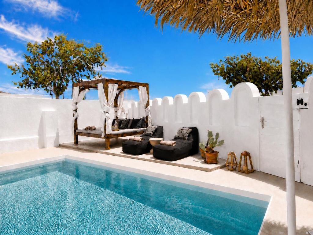 a swimming pool next to a white fence with chairs and a fence at Aegeeis in Perissa