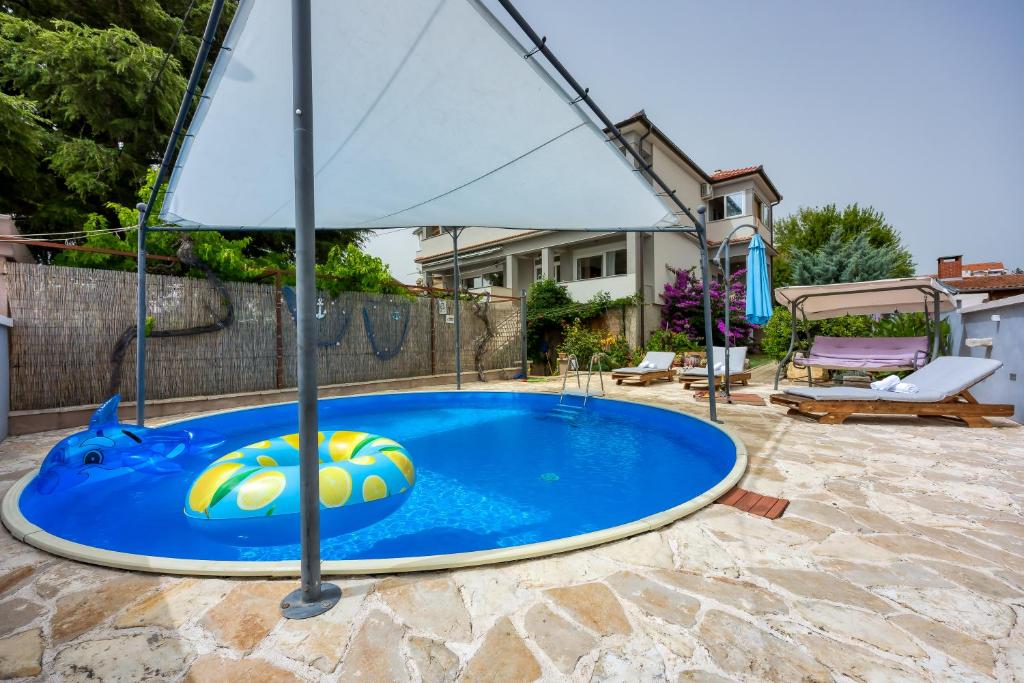 a swimming pool with an umbrella on a patio at Pool & Garden Apartment Bakija - Happy Rentals in Pakoštane