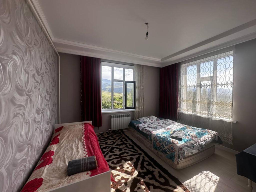 a bedroom with two beds and two windows at Barskoon Guest House in Barskoon