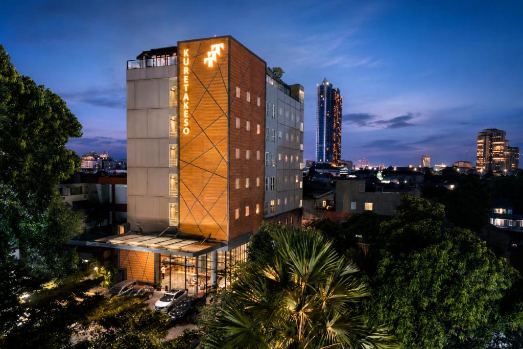 a tall building with lights on it in a city at Kuretakeso Kemang Hotel in Jakarta