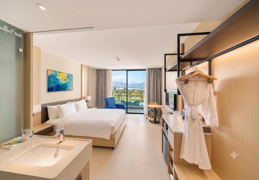 a hotel room with a bed and a sink at The Sea Beach Residences - Arena Cam Ranh Resort in Cam Ranh International Airport
