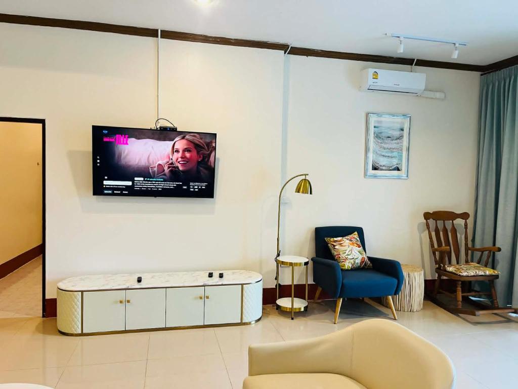 a living room with a couch and a tv on the wall at Coconut hill villa in Trat
