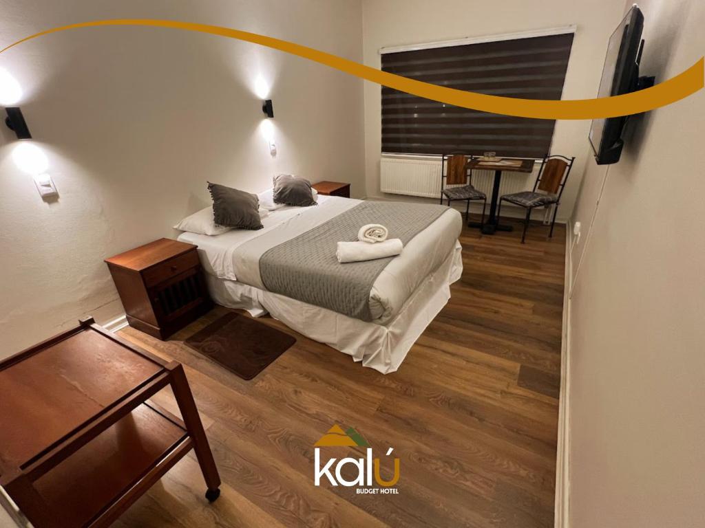 ein Schlafzimmer mit einem Bett und einem Tisch mit einem Stuhl in der Unterkunft Budget Hotel Central in Osorno