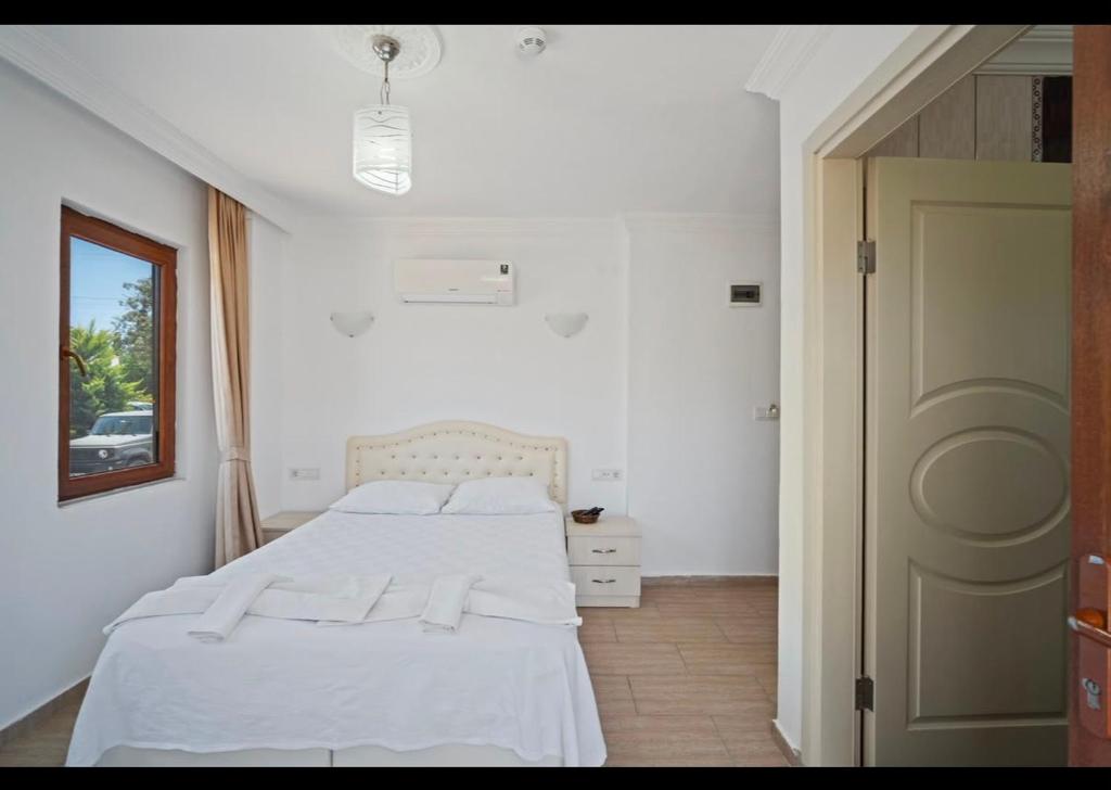 a white bedroom with a bed and a door at Arzu otel apart in Datca