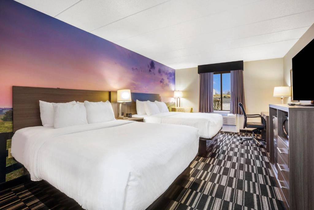 a hotel room with two beds and a flat screen tv at Clarion Pointe Richmond North near University in Richmond