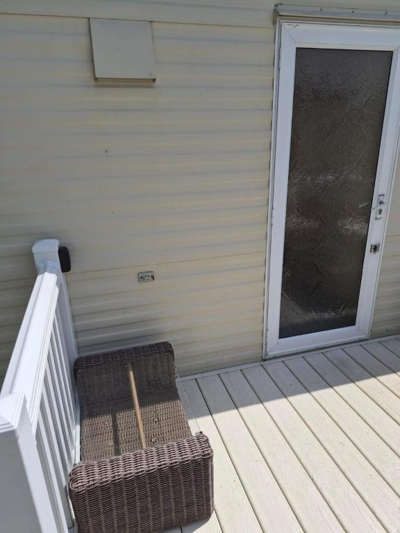 a wicker chair sitting on the porch of a house at Cabin Sleeps 6 with access outdoor Pool in Sandown