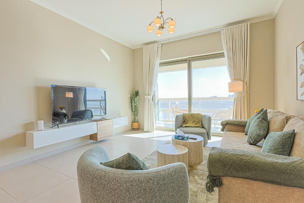 a living room with a tv and a couch and chairs at Saadiyat Serenity 1BR apartment with Beach access in Abu Dhabi