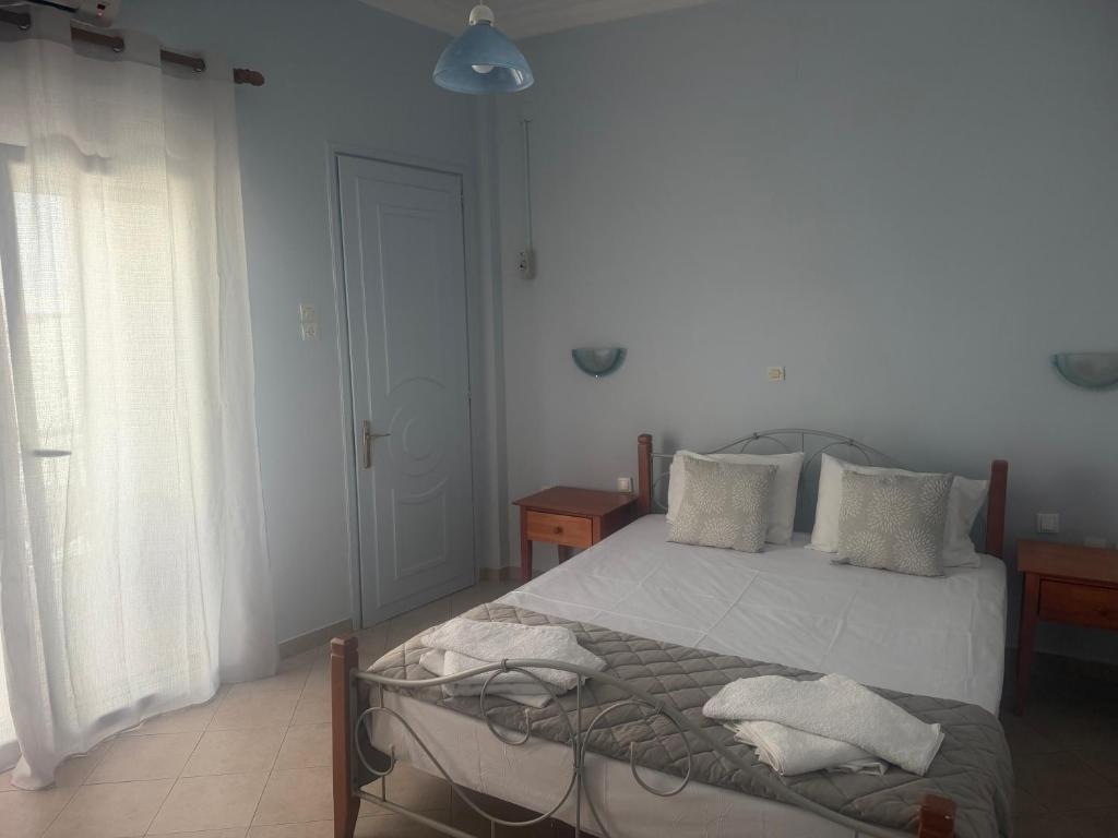 a bedroom with a bed with white sheets and pillows at Apergis Rooms in Ermoupoli