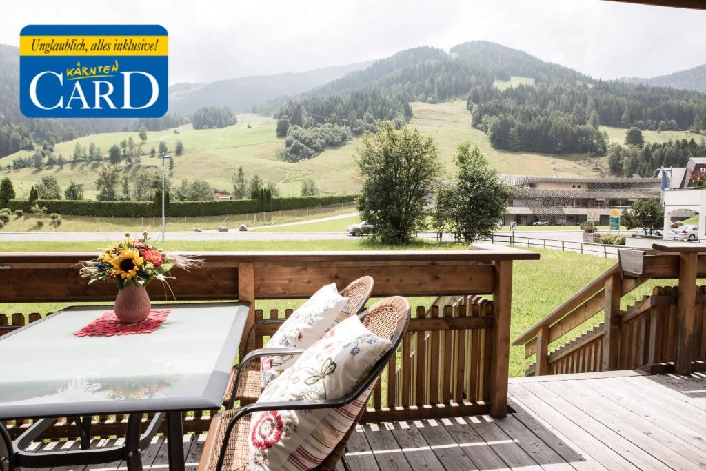 a table and chairs on a deck with a view of the mountains at Residence Mariagrazia - Kärnten Card im Sommer inklusive in Bad Kleinkirchheim