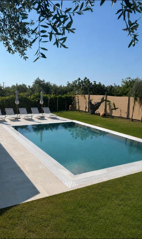 a swimming pool with chairs in a yard at Olive Treasure Villa with Private Pool in Kolymbia