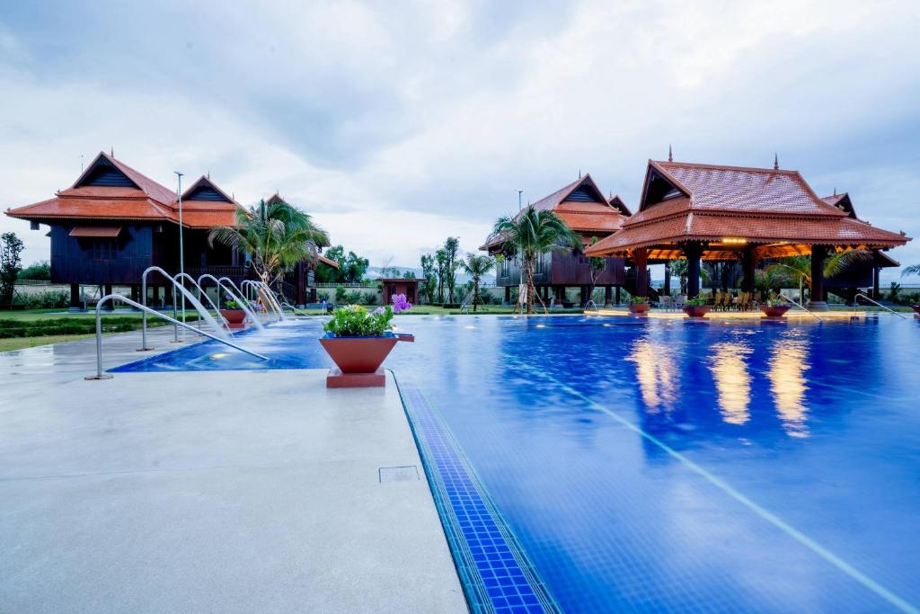 a large swimming pool with several buildings in the background at Heritage Village Resort in Kampot
