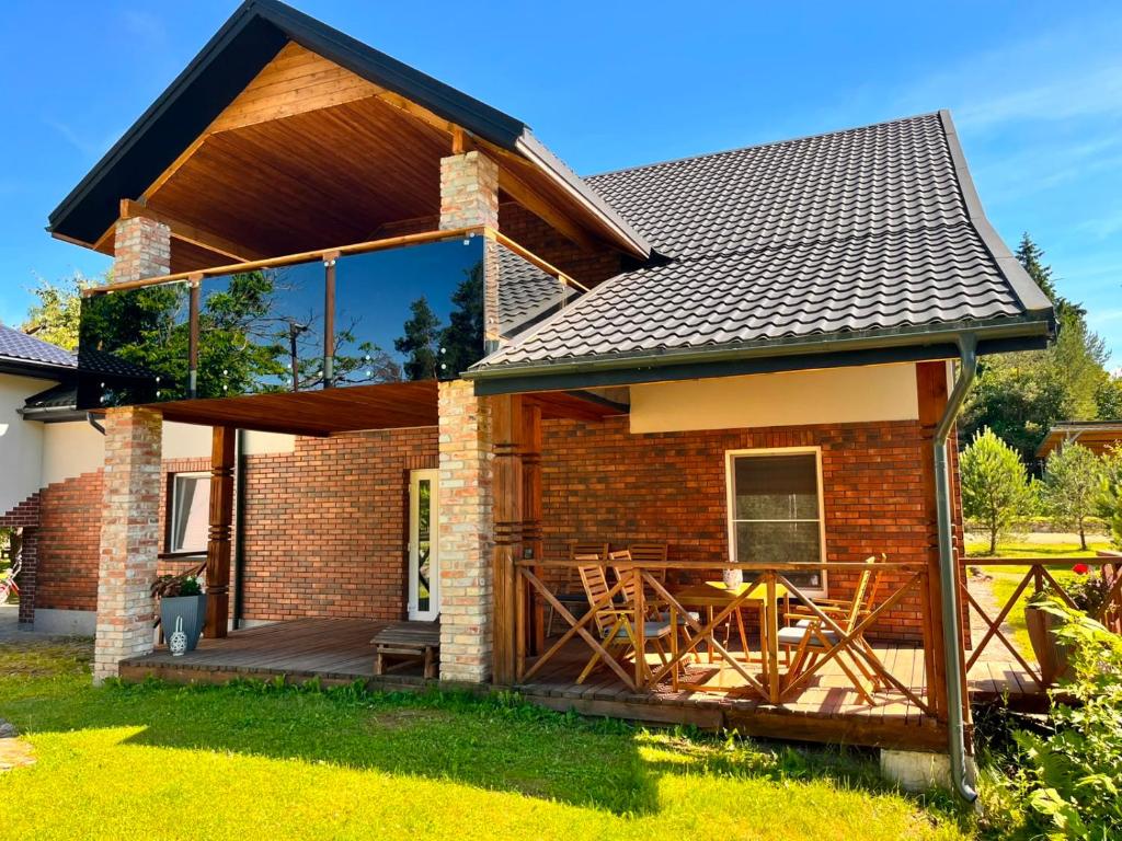 a brick house with a deck with a table at Pakalnės sodyba in Skverbai