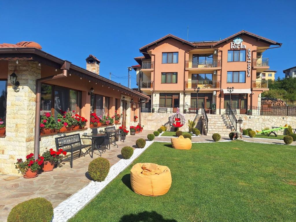 a large building with a yard with benches and flowers at Perla Guest House in Dospat