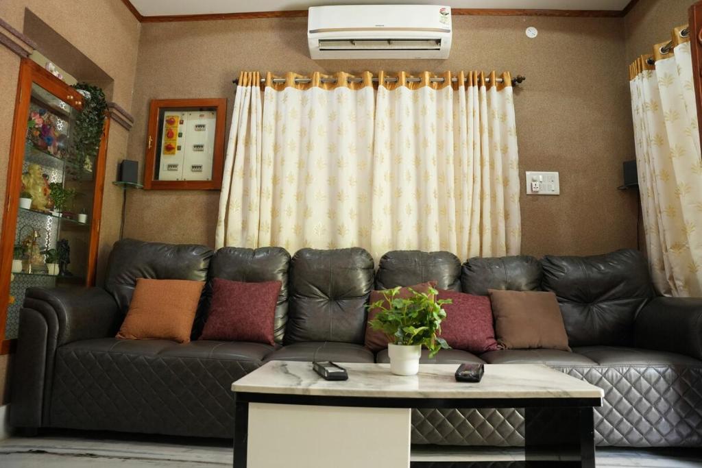 a living room with a leather couch and a table at Manavididillu 4BHK DUPLEX VILLA in Rājahmundry